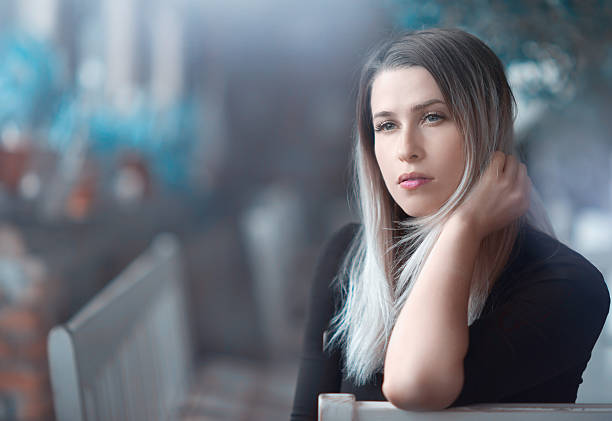 attractive blond hair woman looking away, feeling nostalgic, posing inside restaurant.