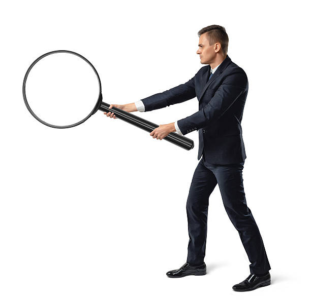 istock Side view of a businessman holding big magnifier with both 603172154