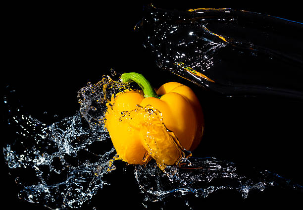 yellow bell pepper with water splash on black