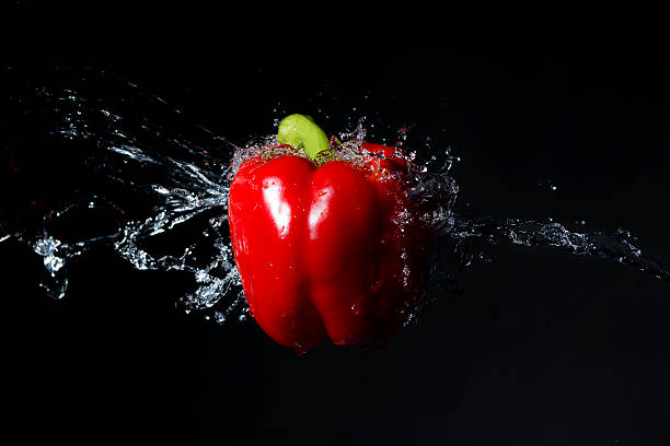 Red bell pepper with water splash on black