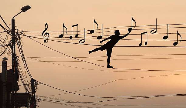Man sits musical notes Sillouthe of a man putting music notes on wires . Concept of a crazy composer musical note photos stock pictures, royalty-free photos & images