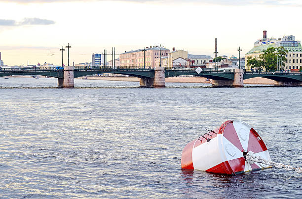 Red and white metal mooring buoys. White anchor chain. River water surface.