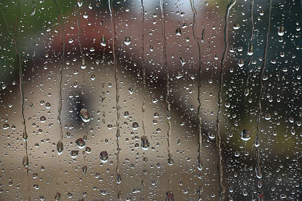 istock Rain drops on window with house and church in background 603175572