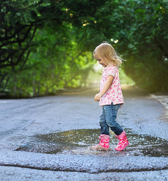 istock Cute little girl jumping into a puddle 603176876