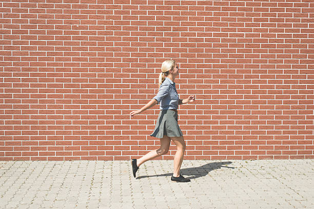istock Young successful business woman walking against brick wall 603177970