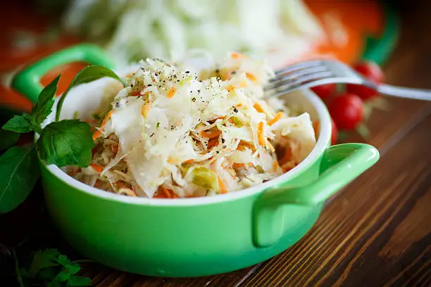 Sauerkraut with carrots in a bowl on a wooden table
