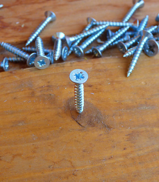 istock Screw in wooden board with fallen screws behind 603181160