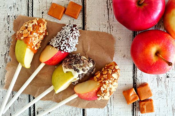 istock Apples slices dipped with chocolate, caramel, scene on white wood 603185148