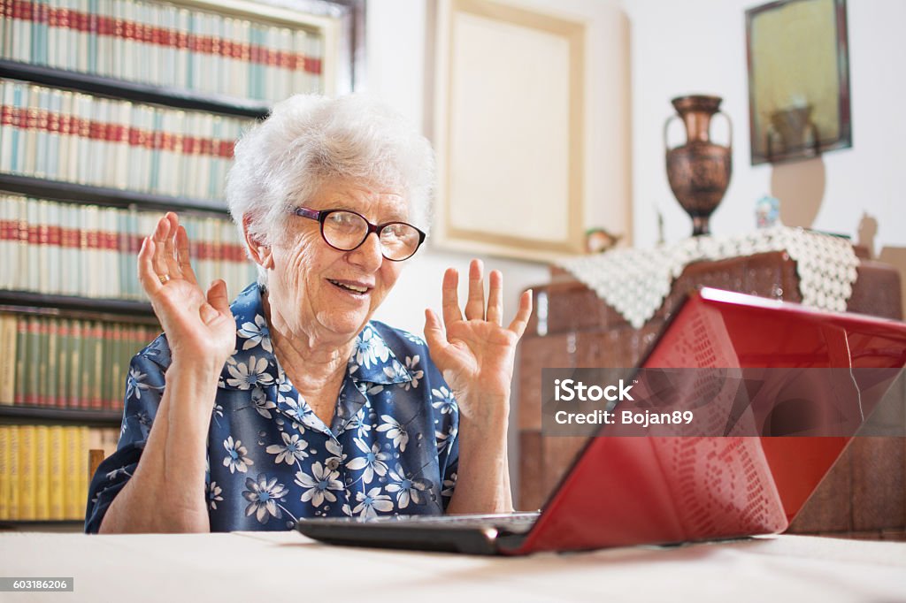 Überraschte Seniorin sitzt zu Hause vor dem Laptop. - Lizenzfrei Alter Erwachsener Stock-Foto