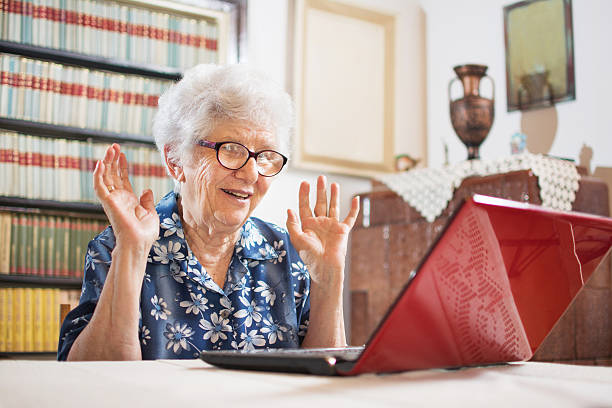 uma idosa surpresa sentada na frente do laptop em casa. - looking at camera senior women laptop only women - fotografias e filmes do acervo