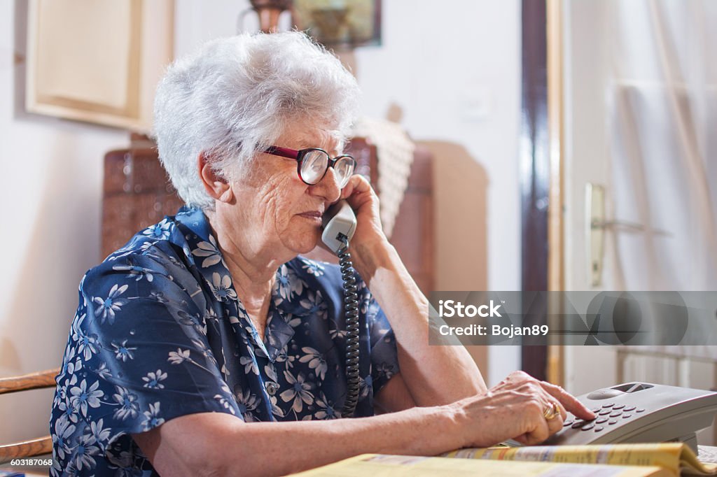 Senior woman dialing a number on her phone at home. Senior Adult Stock Photo