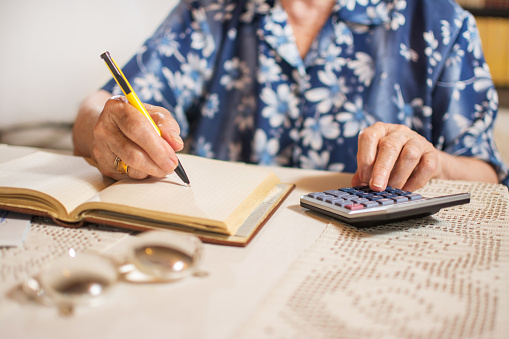 Primer plano de una mujer mayor irreconocible haciendo finanzas en casa. photo