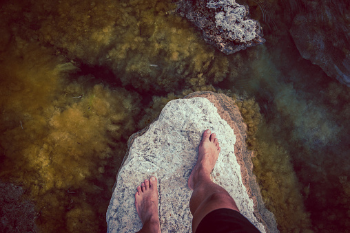 High angle view of male barefoot. Standing on the rock, 
