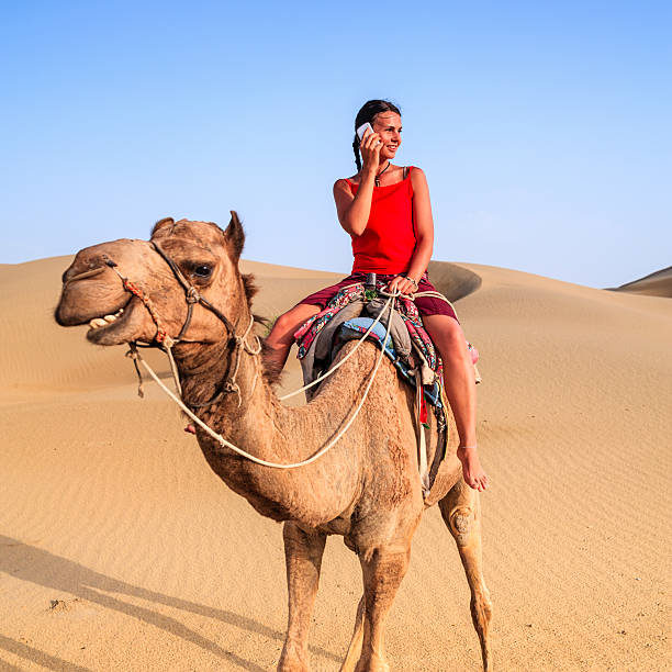 istock Young female tourist using mobile on a camel, Rajasthan, India 603189730