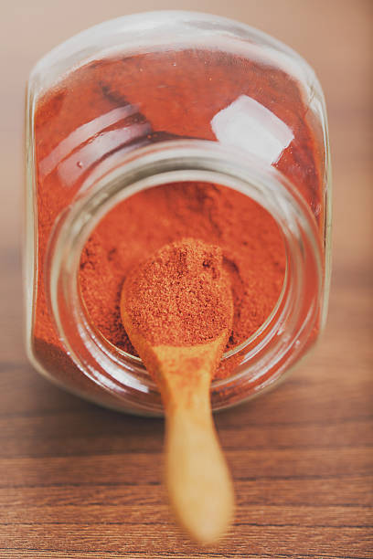 Paprika spice in glass jar with wooden spoon stock photo