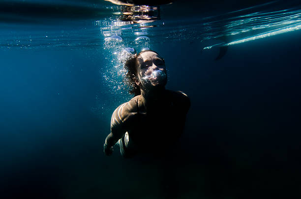 istock Woman blowing bubbles underwater near her surf board 603195876