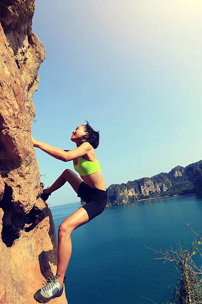 A woman stands on a cliff overlooking the ocean on a tropical island, enjoying the view.