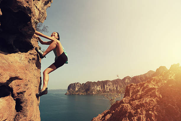 Young Caucasian woman preparing to climb, using chalk powder while looking up.