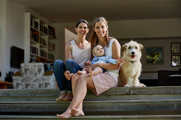 Lesbian couple with baby boy and dog on patio Portrait of smiling lesbian couple with baby boy and dog on patio gay long hair stock pictures, royalty-free photos & images