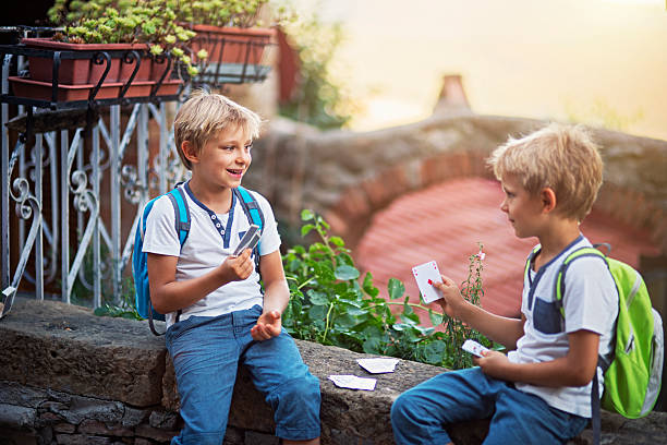 Happy little boys playing cards on a small wall. They don't mind they will skip some classes if they play too long.