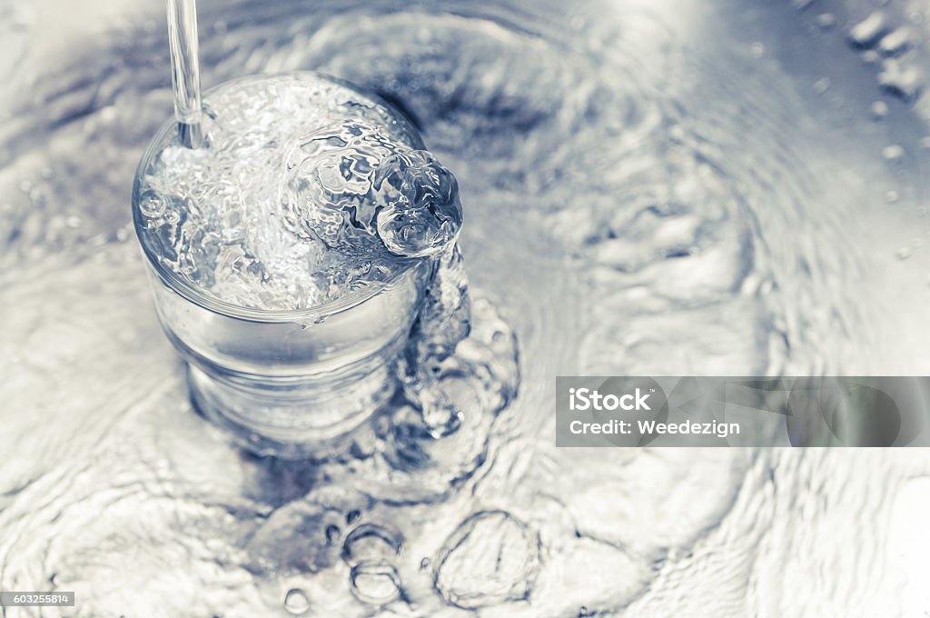 Pouring water from tap to glass on stainless steel Pouring water from tap to glass on stainless steel stand at kitchen,tone filtered. Faucet Stock Photo