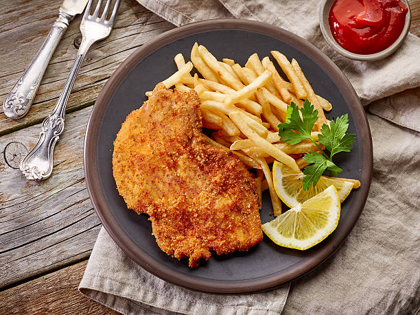 schnitzel and fried potatoes schnitzel and fried potatoes on dark plate, top view breaded photos stock pictures, royalty-free photos & images