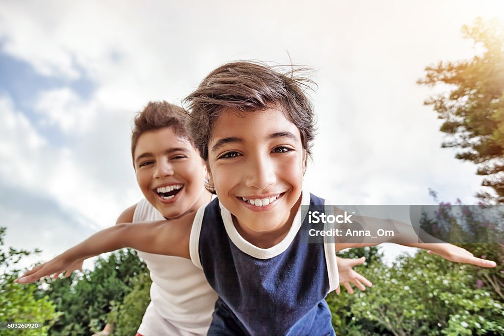 Happy brothers playing outdoors Happy brothers having fun outdoors, playing as if flying, two active boys spending summer holidays with pleasure in a countryside Child Stock Photo