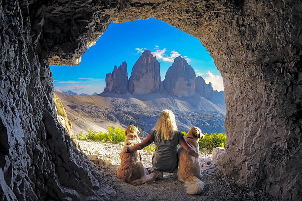 女性は洞窟、ドロミテから犬と一緒に景色を楽しむ - tre cime di lavaredo ストックフォトと画像