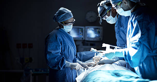 They are a team of dedicated surgeons Shot of a team of surgeons performing a surgery in an operating room surgery stock pictures, royalty-free photos & images