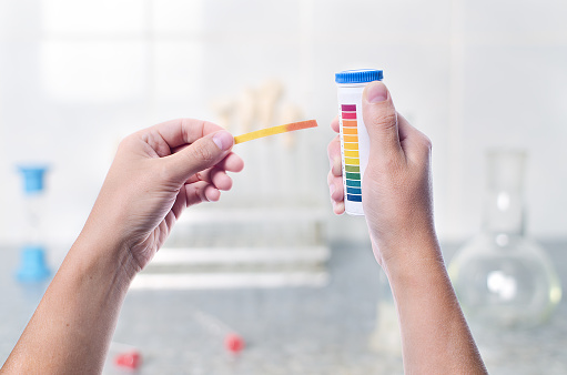 Scientist working colored litmus paper in hand in a lab, first-person, on a light background research lab, chemist in the lab examines a sample of contamination