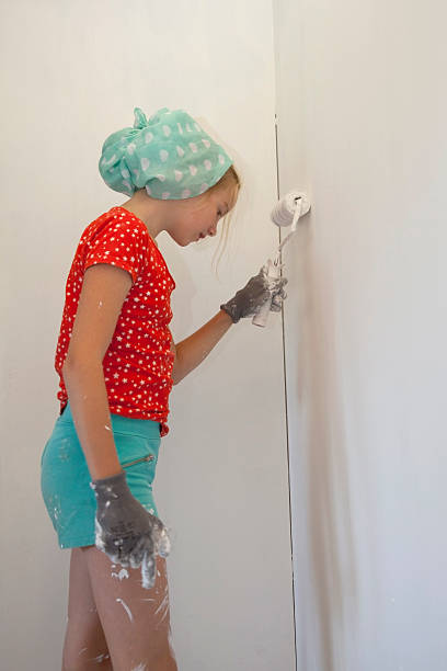 istock young white girl with gloves and paint roller 603268820
