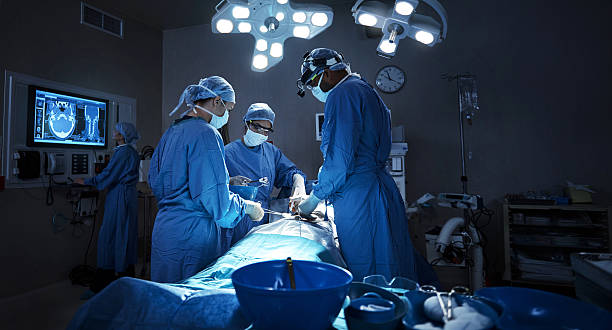 They diligently stay current in a very complicated field Shot of a team of surgeons performing a surgery in an operating room operating room photos stock pictures, royalty-free photos & images