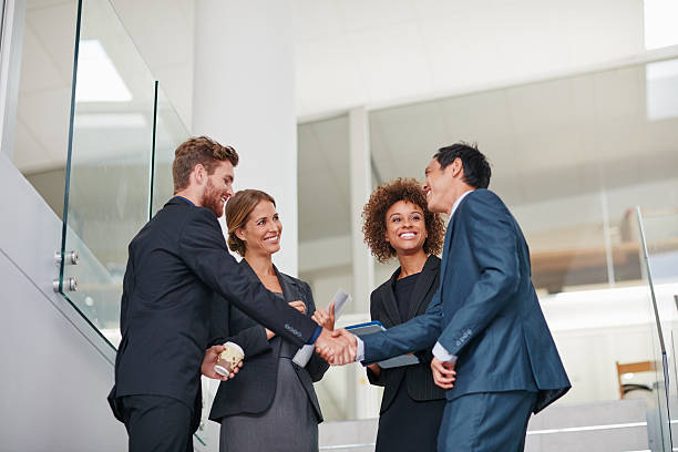 Merging their talents to form the ultimate team Cropped shot of businesspeople shaking hands in a modern office global business handshake stock pictures, royalty-free photos & images