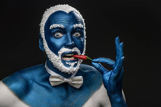 Man with snowy hair and beard eating chili pepper stock photo