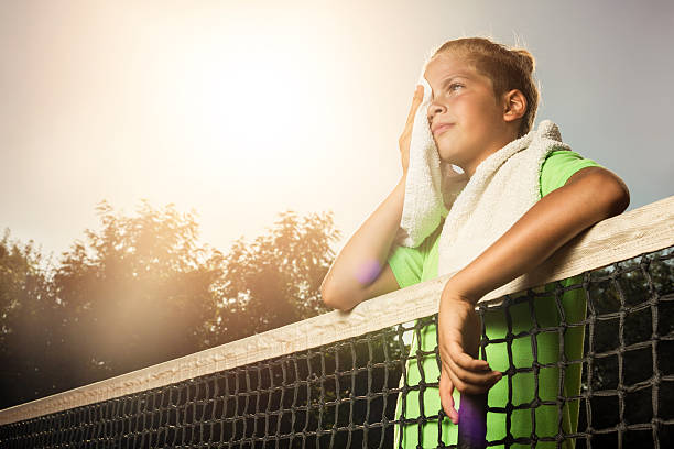 スポーツトレーニングの後に汗を拭く疲れた小さなテニス選手。 - tennis court sports training tennis net ストックフォトと画像