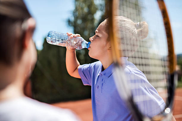 menino sedento bebendo água na quadra de tênis. - water child bottle little boys - fotografias e filmes do acervo