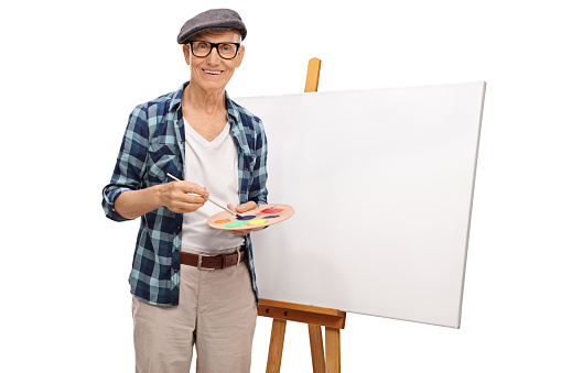 Mature painter posing next to a blank canvas isolated on white background