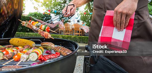 Man Grilling Meat On Garden Barbecue Party Stock Photo - Download Image Now - Grilled, Men, Outdoors