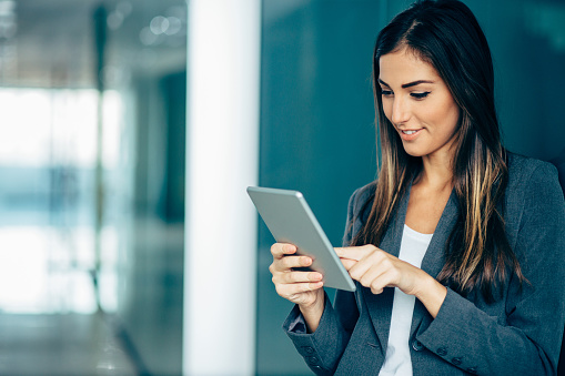 Portrait of young woman in business wear holding a digital tablet, with copy space