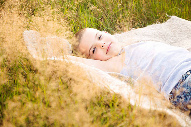 istock Cheerful boy lying down in grass in summer 603284724