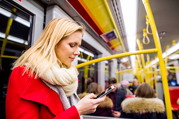 istock Beautiful young woman with smart phone in subway train 603285400