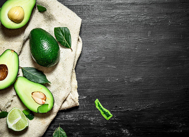 istock Avocado, lime and leaves . On black wooden background. 603285608