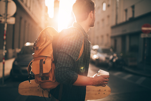 Portrait of a skater boy holding his skateboard and a cup of coffee to go