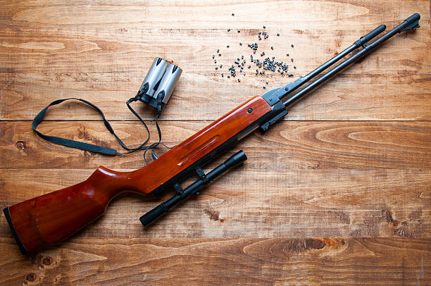 istock Air rifle, pellet and binoculars on a wooden background 603286460