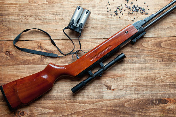 istock Air rifle, pellet and binoculars on a wooden background 603286710