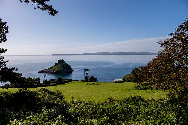 Beautiful summer scene framed by trees looking down to the Devon coast at Meadfoot Bay Torquay with Thatcher's Rock.