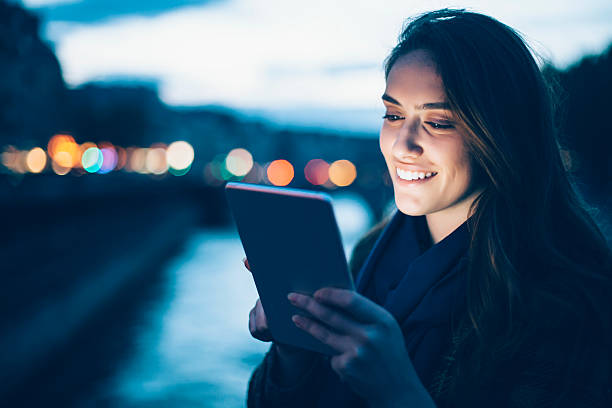 istock Cheerful young woman using digital tablet on bridge by night 603301856