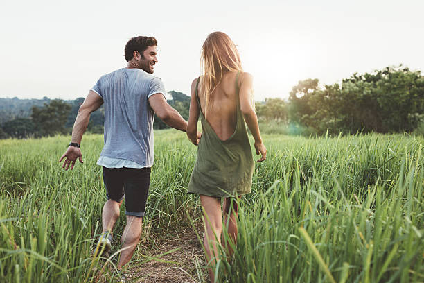 istock Young couple walking through grassy field 603313666