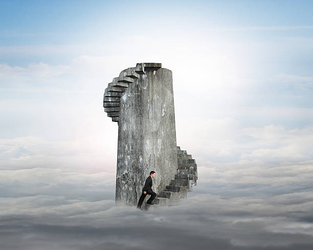 istock Businessman climbing concrete spiral staircase tower over clouds 603314076