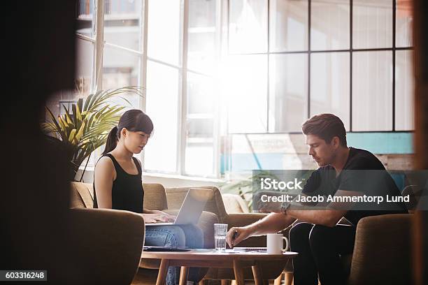 Two Businesspeople Meeting In Lobby Area Of Modern Office Stock Photo - Download Image Now